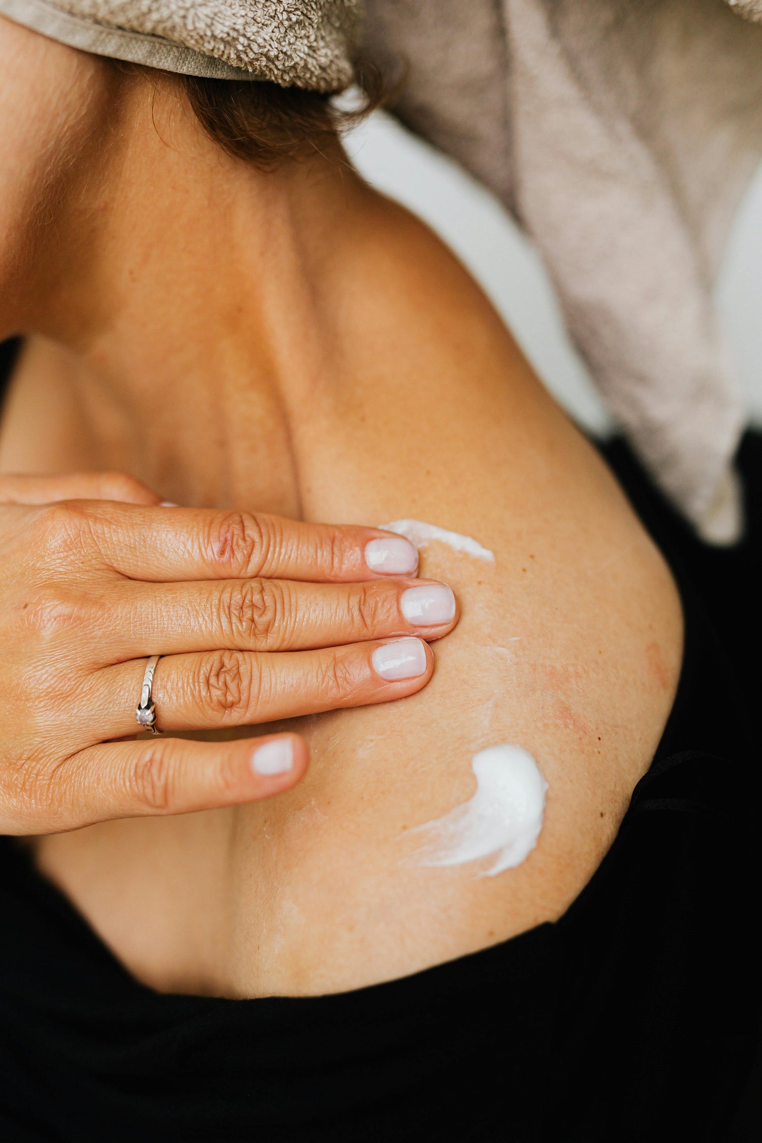 Applying Luxury, High-Quality, All-Natural Skincare solutions on shoulder skin for hydration and nourishment